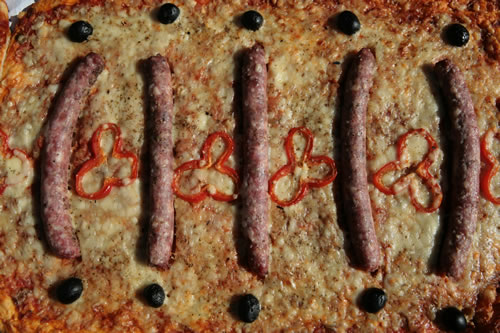 Coca amb salsitxes, pebrot i olives