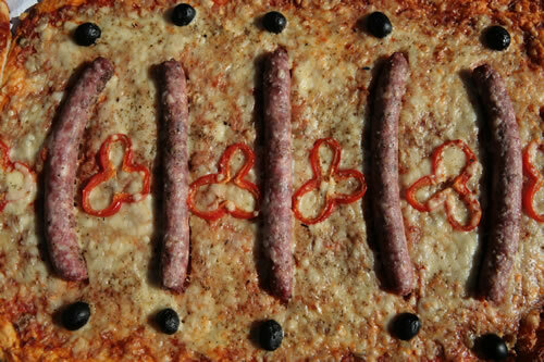 Coca amb salsitxes, pebrot i olives
