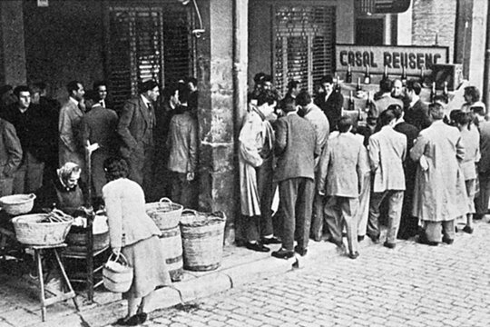 Foto antiga d'una rifa de panellets al carrer, a Reus